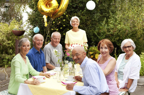 Ältere Menschen feiern ihren Geburtstag im Garten, lizenzfreies Stockfoto