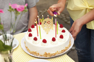Kerzen auf der Torte zum 80. Geburtstag von Hand anzünden - MFRF00766