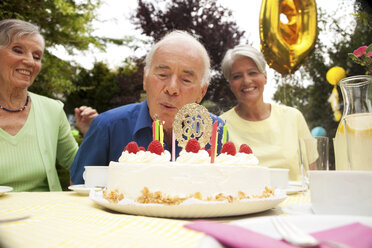 Älterer Mann bläst Kerze auf 80. Geburtstagstorte aus - MFRF00771
