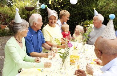 Extended family and friends having birthday party in garden - MFRF00790