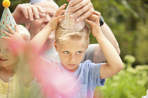 Junge setzt sich Partyhut auf, lizenzfreies Stockfoto