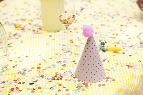 Party hat and party blower on table with confetti - MFRF00813