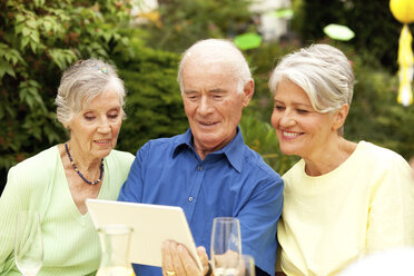 Senior man looking at digital tablet with guests - MFRF00825