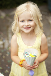 Little girl holding party hat filled with party blowouts - MFRF00828