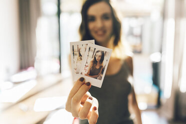 Junge Frau hält Polaroids von sich selbst - GIOF01635