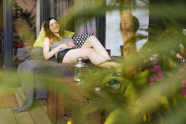 Entspannte junge Frau beim Musikhören auf der Terrasse - GIOF01636