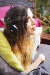 Junge Frau, die mit Kopfhörern Musik hört - GIOF01637