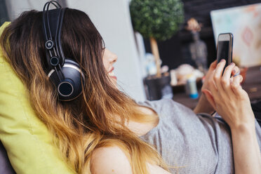 Young woman wearing headphones using cell phone - GIOF01638
