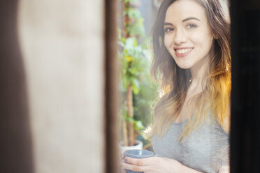 Portrait of smiling young woman drinking coffee - GIOF01640