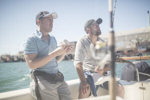 Zwei Männer machen Mittagspause auf einem Boot mit Angelruten - ZEF11760