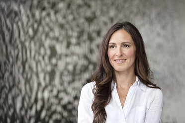 Portrait of confident businesswoman in front of rippled wall - PESF00370