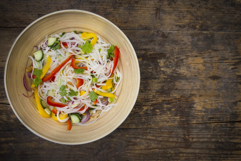 Bowl of glass noodle salad with vegetables on dark wood stock photo
