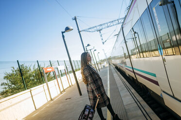 Woman walking towards a train car at a station - KIJF00864