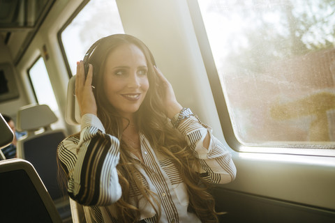 Frau in einem Zug, die mit Kopfhörern Musik hört, lizenzfreies Stockfoto