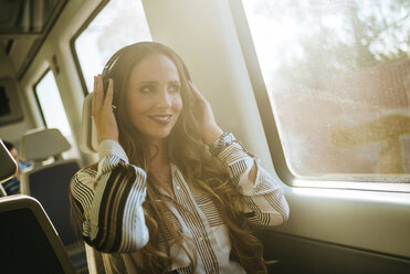 Woman on a train listening to music with headphones - KIJF00875
