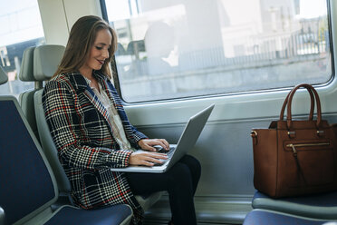 Geschäftsfrau in einem Zug mit einem Laptop - KIJF00877