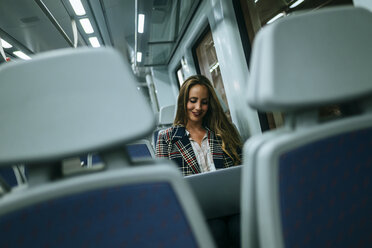 Businesswoman on a train using a laptop - KIJF00879