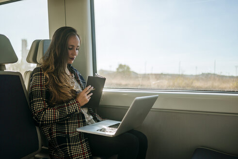 Geschäftsfrau in einem Zug mit Notebook und Laptop - KIJF00880