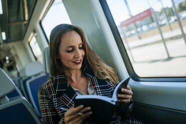 Businesswoman on a train with notebook - KIJF00887