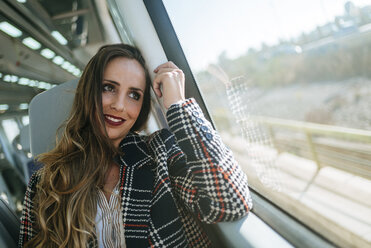 Smiling woman on a train looking out of window - KIJF00889