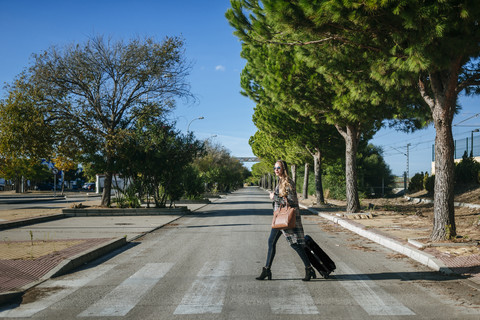 Frau mit Koffer beim Überqueren der Straße, lizenzfreies Stockfoto
