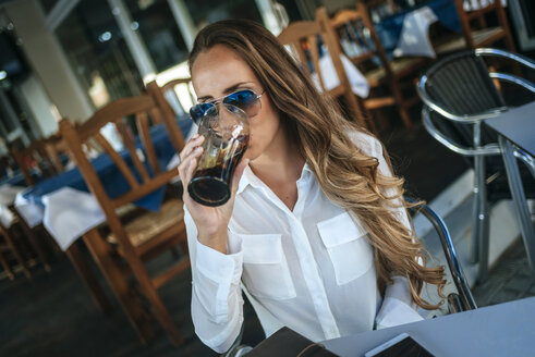 Frau trinkt eine Cola in einem Straßencafé - KIJF00908