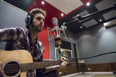 Mann spielt Gitarre in einem Aufnahmestudio während einer Musikaufnahme - ABZF01541