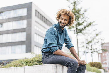 Young man sitting on wall, smiling - JOSF00413