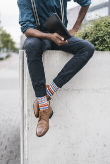 Young man sitting on wall, holding laptop - JOSF00414