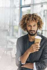 Young businessman drinking coffee from disposable cup - JOSF00433