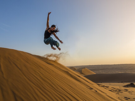 Oman, Al Raka, Junge Frau springt von einer Düne in der Wüste Rimal Al Wahiba - AMF05082