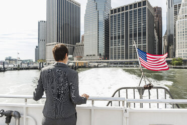 USA, Brooklyn, Rückenansicht einer Geschäftsfrau auf einem Boot mit Blick auf Manhattan - UUF09247