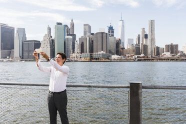 USA, Brooklyn, happy businesswoman taking selfie in front of Manhattan skyline - UUF09252