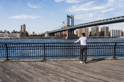 USA, Brooklyn, Rückenansicht einer Geschäftsfrau mit Blick auf den East River - UUF09267