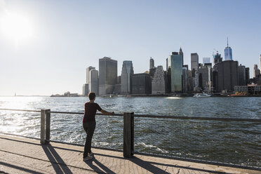 USA, Brooklyn, back view of woman looking at Manhattan skyline - UUF09275