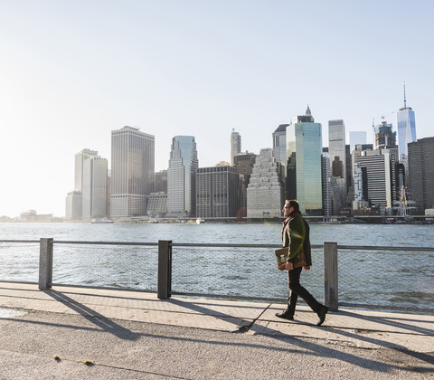 USA, Brooklyn, Geschäftsmann mit Aktentasche vor der Skyline von Manhattan, lizenzfreies Stockfoto