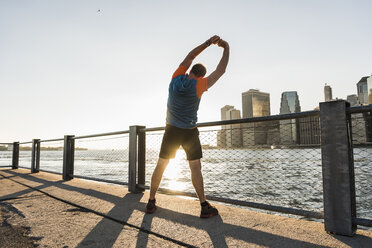 USA, Brooklyn, back view of man doing stretching exercises in the evening - UUF09310