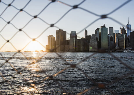 USA, Brooklyn, view to Manhattan through fence at twilight - UUF09319