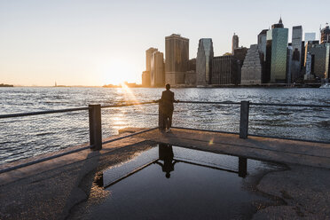 USA, Brooklyn, back view of woman leaning on railing looking at view at sunset - UUF09320