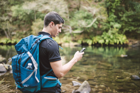 Wanderer schaut in der Natur auf sein Smartphone, lizenzfreies Stockfoto