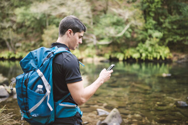 Wanderer schaut in der Natur auf sein Smartphone - RAEF01547