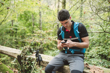 Wanderer schaut in der Natur auf sein Smartphone - RAEF01554