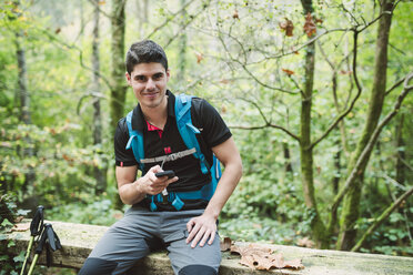 Porträt eines lächelnden Wanderers mit Smartphone in der Natur - RAEF01555