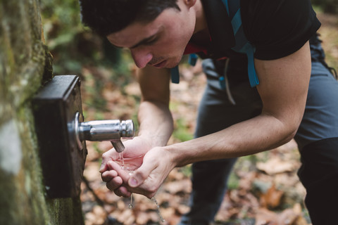 Wanderer trinkt Wasser aus einem Brunnen, lizenzfreies Stockfoto