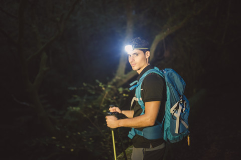 Wanderer mit einer Stirnlampe im nächtlichen Wald, lizenzfreies Stockfoto