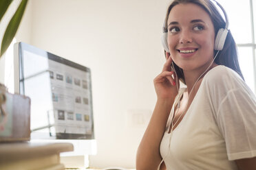 Portrait od smiling young woman with headphones at computer - SIPF01111