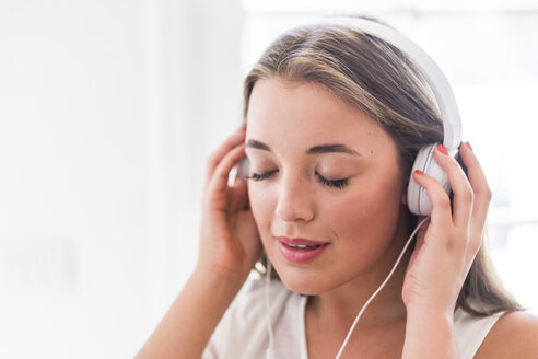 Junge Frau mit geschlossenen Augen hört Musik mit Kopfhörern - SIPF01116