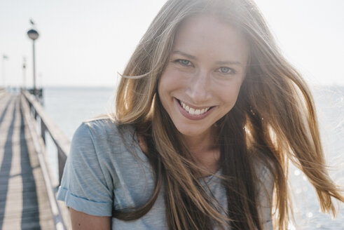 Porträt einer glücklichen jungen Frau auf einem Steg im Gegenlicht - KNSF00666
