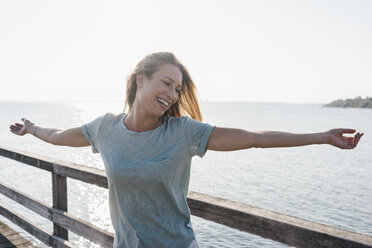 Happy young woman on jetty at backlight - KNSF00669