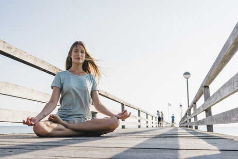 Young woman practising yoga on jetty - KNSF00671